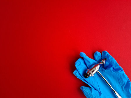 Neurological hammer gloves for the work of neurologist on red background. Neurological diseases diagnosis and treatment conceptの写真素材