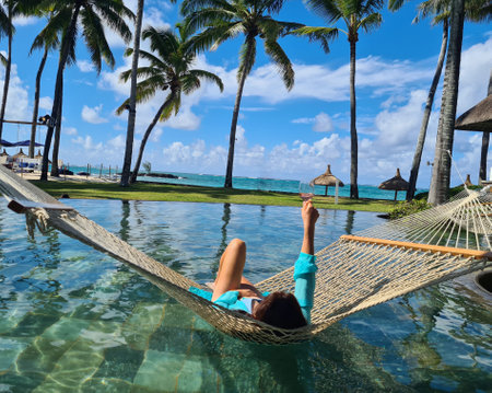 Woman enjoys wine in hammock by sea or ocean. Tourism travel relaxation and enjoyment paradise islandの写真素材