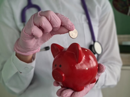 Doctor throws coin with red pig into piggy bank. Health insurance and budgetの写真素材