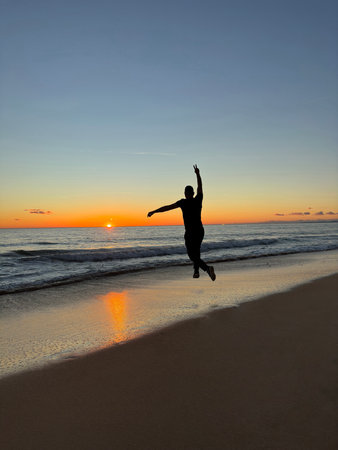 Happy free male tourist traveler at sea or ocean sunset. Wonderful beautiful world and planetの写真素材