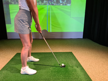 Golf player plays golf indoors. Golf driving range with simulator screenの写真素材