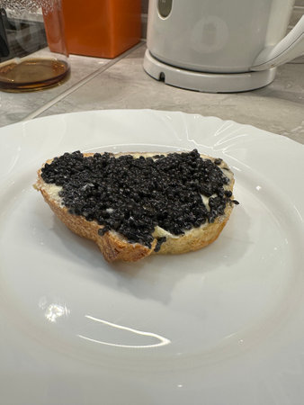 Sandwich with black caviar on white plate in kitchen. Benefits of caviar and vitaminsの写真素材