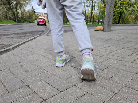 Children feet in sneakers makes step along the road. summer walk conceptの写真素材