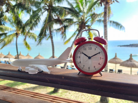 Red alarm clock sea beach and passenger plane. Tropical sea in summer seasonの写真素材