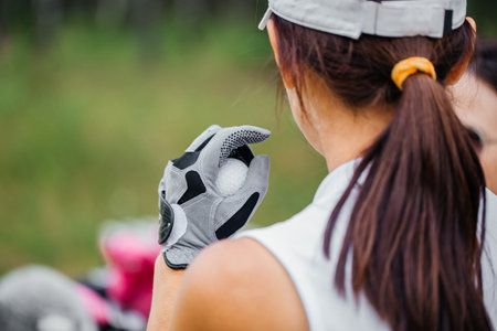 Hand shows golf ball on beautiful golf course. Golfer with ball and clubの写真素材