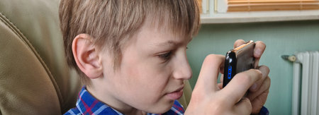 leisure kids and technology internet addiction. Boy with smartphone sending text message or playing game at homeの写真素材