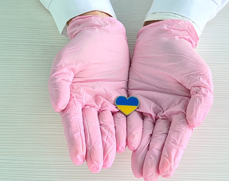 Doctors hands wearing surgical gloves holding Ukraine flag heartの写真素材
