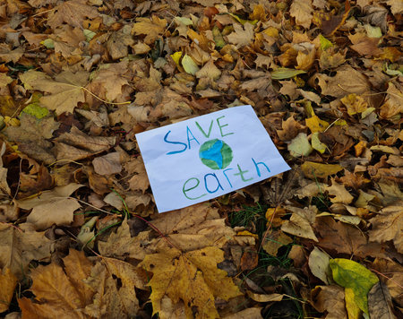 Poster with the inscription save planet in autumn forest among plants. Ecological disaster on planetの写真素材