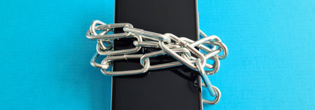 Black smartphone wrapped in metal chain closeup. Phone lockの写真素材