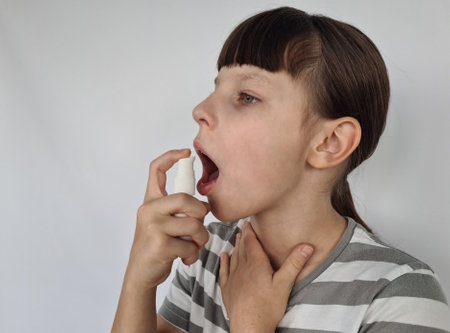 Girl child with spray for sore throat. Sore throat, flu and seasonal diseasesの写真素材