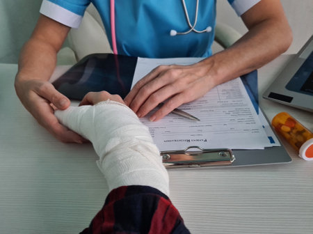 Injured patient showing broken wrist and arm with plaster cast to doctor in hospital office or emergency room. Sprain and stress fracture or repetitive hand injuryの写真素材