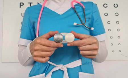 Ophthalmologist holds contact lenses and an eye chart closeup. Vision test chart and lens selectionの写真素材