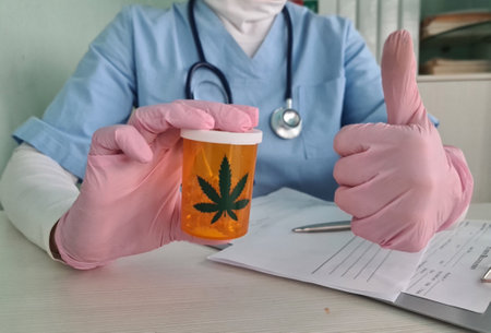 General practitioner holding a jar of CBD oil pills in hand showing thumbs up. Sign approved cannabis recommendationの写真素材