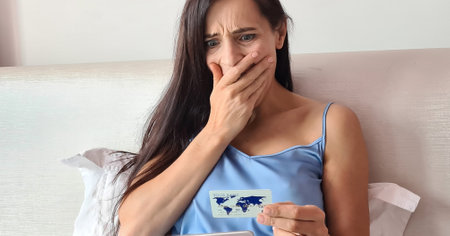 Pretty woman in bed with laptop and credit card shocked and afraid to make a mistake. Theft of cash...