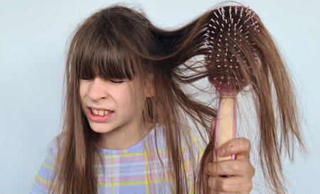 Frightened and shocked caucasian girl with long hair on comb. Teenager child looking at a comb with piece of hairの写真素材
