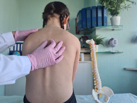 Chiropractor examining child with back pain in clinic. Spinal problem scoliosis and stoop in childrenの写真素材