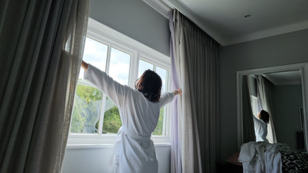 Woman in Robe Standing in Front of Windowの写真素材