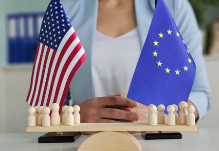 Flags of the European Union and the United States with wooden figures symbolizing diplomacy and division. Europe vs. America and conflictの写真素材
