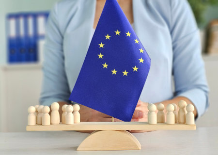 European Union flag displayed with wooden figures representing cooperation and unity in a formal settingの写真素材