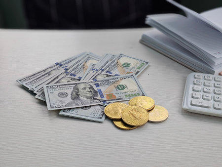 Stacks of currency and gold coins displayed during a financial discussionの写真素材
