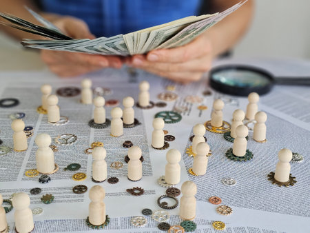 Wooden figures of people of the society of employees with gears and cash dollars. Hiring and team building and earnings on employeesの写真素材