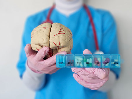 Healthcare professional displays a brain model and weekly pill organizer highlighting the importance of mental health managementの写真素材