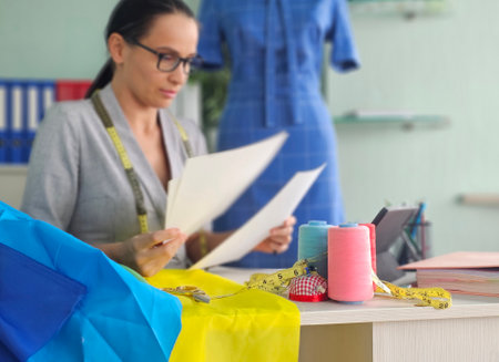 Fashion designer reviewing patterns and fabric choices in a bright studio settingの写真素材