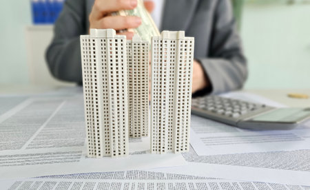 Model skyscrapers and cash transaction in a corporate office setting during financial planningの写真素材