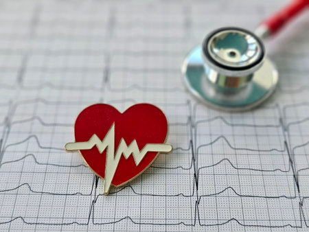 A heart shaped pin featuring a heartbeat symbol is placed on an ECG paper