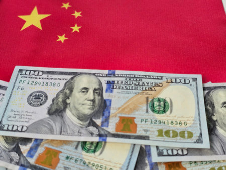 Hundred dollar bills on display with the Chinese flag in the background during a financial discussionの写真素材