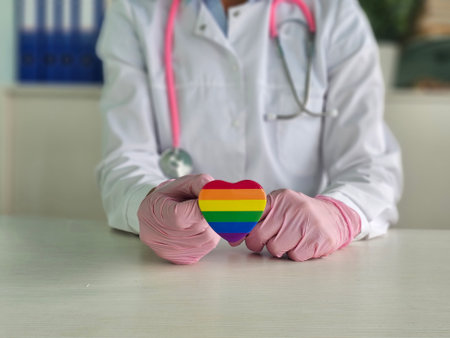 A healthcare professional holding a rainbow heart symbol in a medical setting to promote inclusivity and support for LGBTQ rightsの写真素材