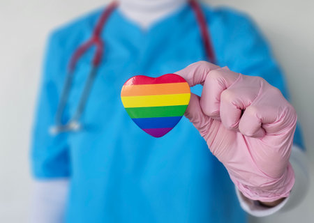 Healthcare professional holds rainbow heart symbol in support of LGBTQ community during health awareness campaignの写真素材