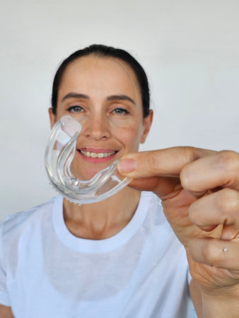 Woman showcasing a clear dental mouthguard while smiling for improved oral health