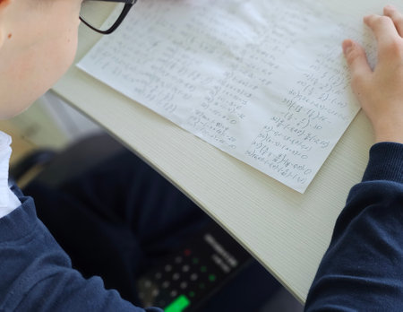 Student holding smartphone screen while taking math exam in school