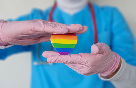 Health professional holds rainbow heart symbol promoting inclusivity and support for LGBTQ community...