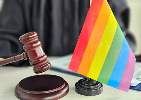 Judicial gavel beside a rainbow flag representing LGBTQ rights in legal settingの写真素材