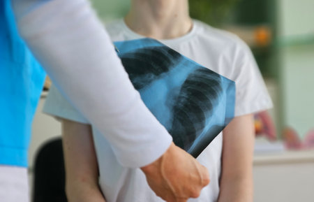 Medical professional examines chest X-ray of a patient in a healthcare settingの写真素材