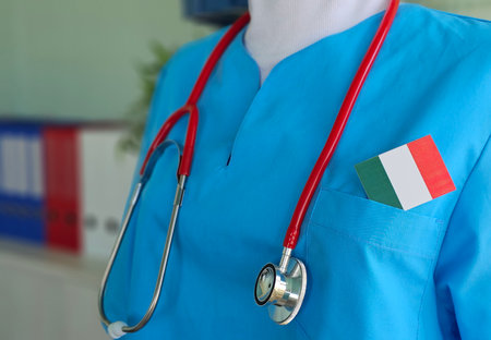 Healthcare professional in blue scrubs with stethoscope and Italy flag on pocket in a medical settingの写真素材