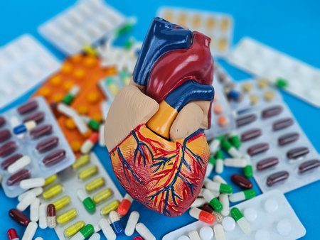 Heart model surrounded by various pills and capsules on a bright blue surfaceの写真素材
