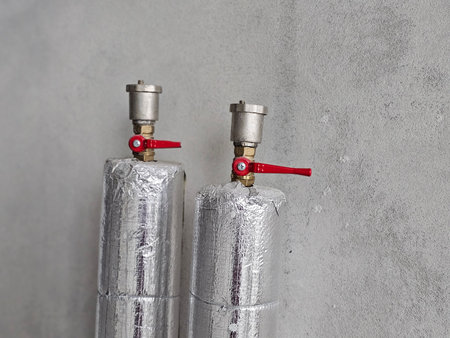 Metallic gas cylinders with valves for industrial use displayed against a textured gray wallの写真素材