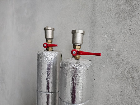 Industrial gas cylinders with safety valves displayed against a concrete wallの写真素材