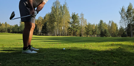 Golfer preparing to take a swing on a clear autumn day at a scenic golf course