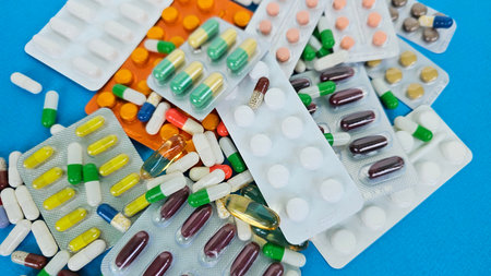 Various medications displayed on a table with colorful capsules and tablets for health and wellnessの写真素材