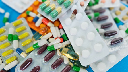 Collection of various medicines and capsules arranged on a colorful surface for health and wellness...