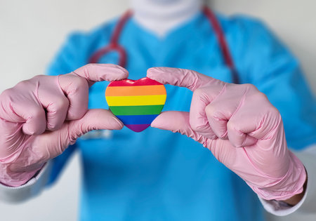 Health worker holds rainbow heart to show support for LGBTQ community during healthcare awareness eventの写真素材