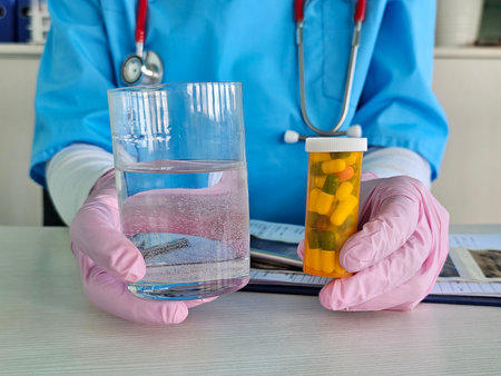 Healthcare professional holding a glass of water and a prescription bottle in a medical settingの写真素材