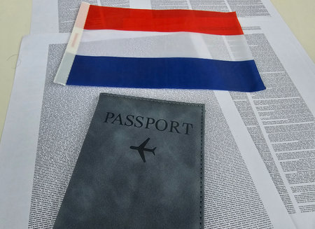 Dutch passport and flag laid on text background with travel context and personal identification detailsの写真素材