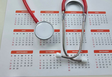 Stethoscope rests on a calendar highlighting important dates for the medical professionの写真素材