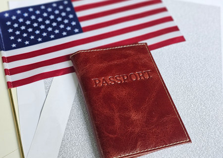 Passport and American flag on a travel themed background with open pages