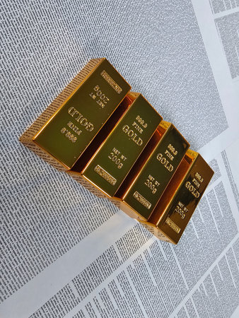 Gold bars stacked together on a newspaper with financial news in the background highlighting investment opportunitiesの写真素材